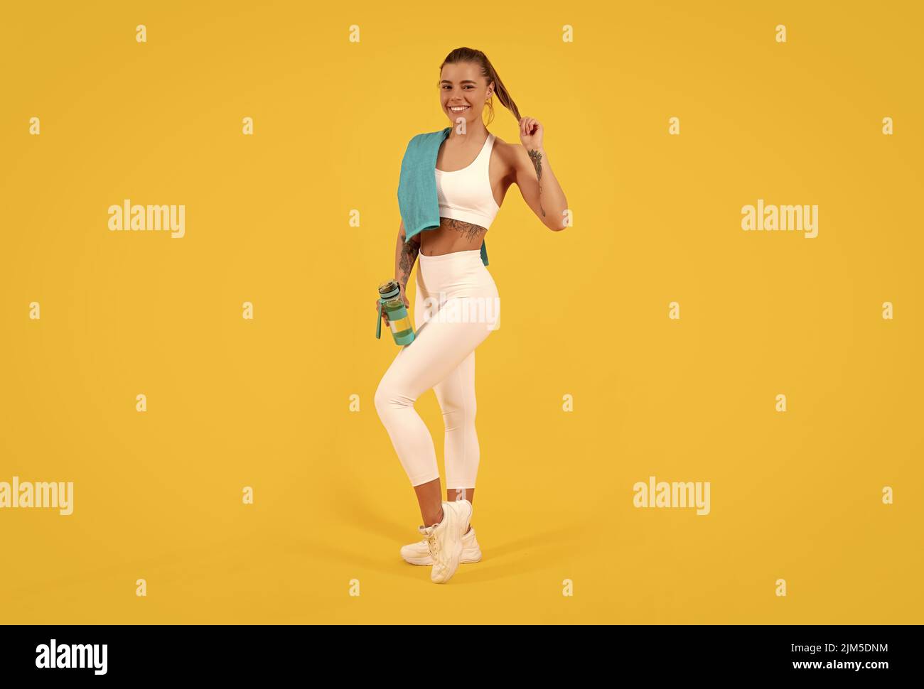 Glückliche Sportfrau mit Wasserflasche auf gelbem Hintergrund Stockfoto