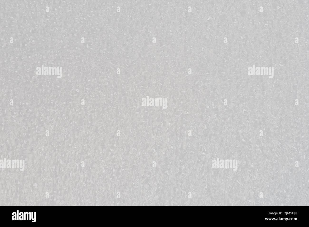 Makro-Nahaufnahme mit weißem Weichschaum-Hintergrund. Muster aus Polyesterpartikeln Stockfoto