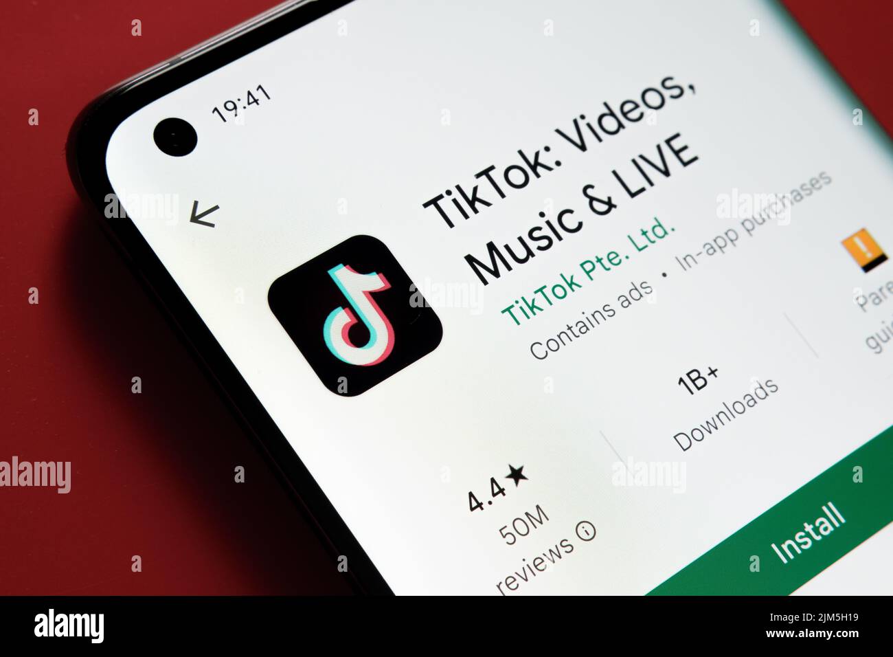 TikTok App im Google Play Store auf dem Smartphone-Bildschirm auf rotem Hintergrund angezeigt. Nahaufnahme mit selektivem Fokus. Stafford, Vereinigtes Königreich, Stockfoto