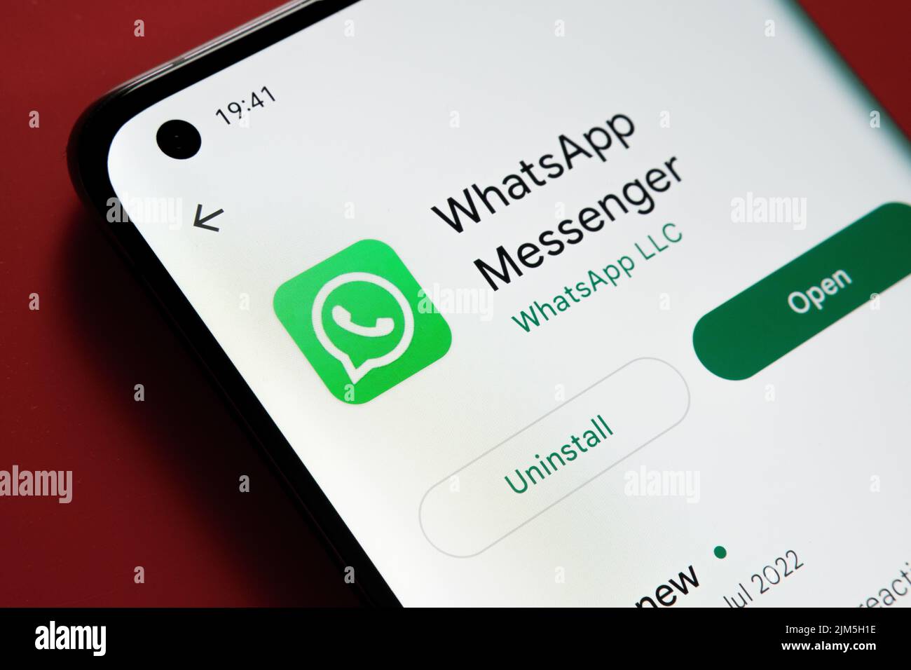 WhatsApp App im Google Play Store auf dem Smartphone-Bildschirm auf rotem Hintergrund gesehen. Nahaufnahme mit selektivem Fokus. Stafford, Großbritannien Stockfoto