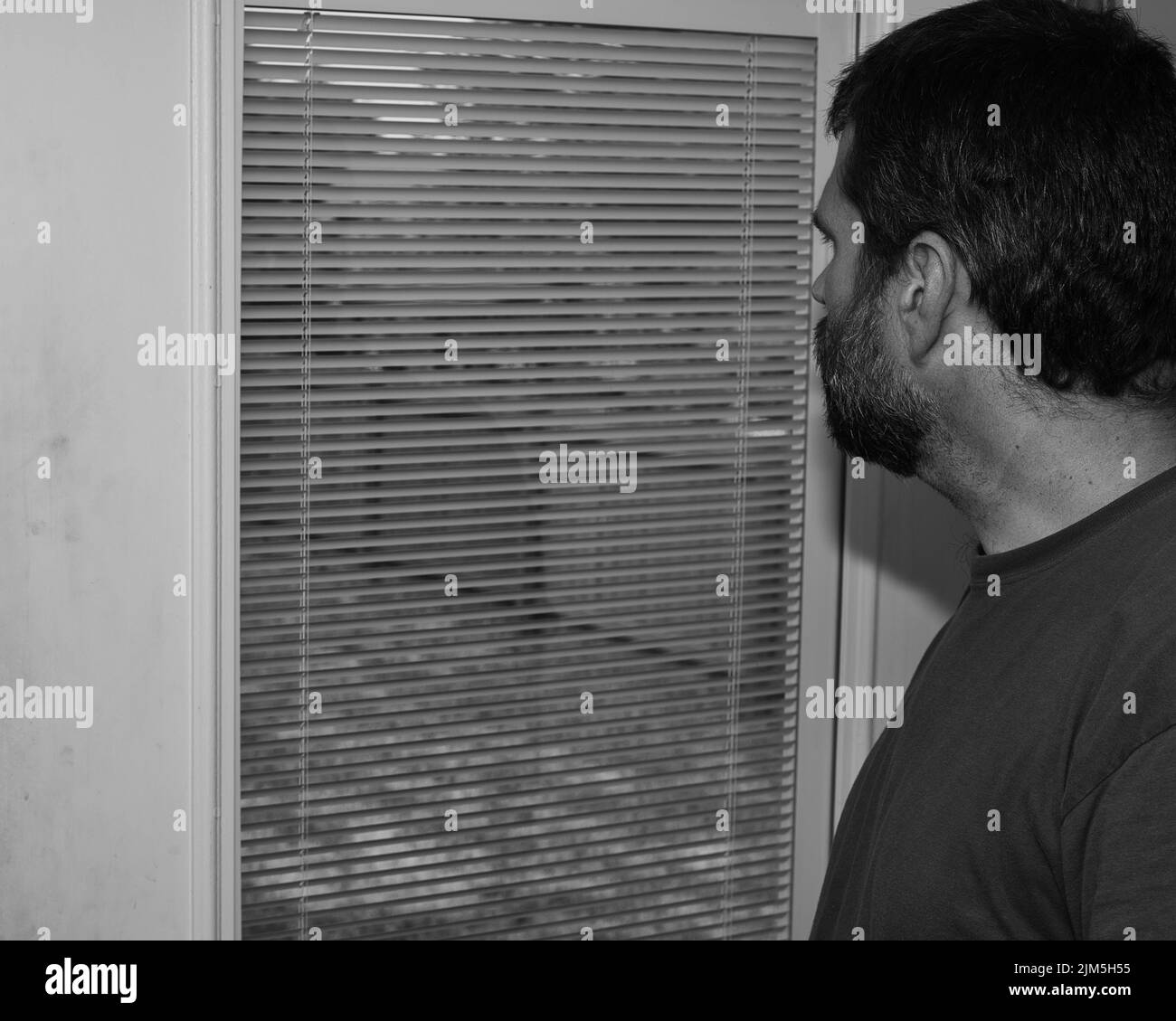Saisonale affektive Störung - TRAURIG - depressiver Mann, der ziellos aus dem Fenster schaut - psychische Gesundheit Stockfoto