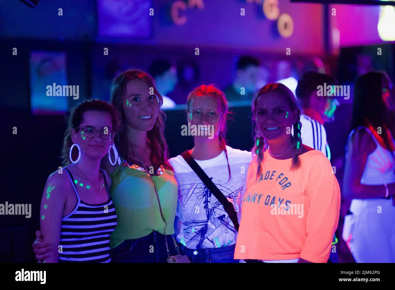 Vier schöne glückliche junge Freunde, die lächeln und während einer Party zusammen posieren Stockfoto