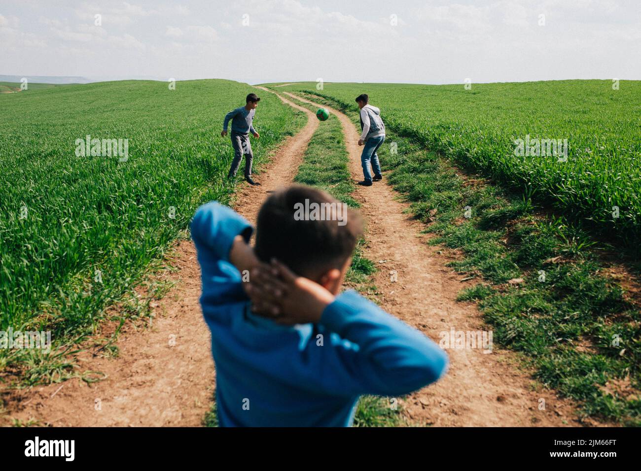Ein Blick auf drei Schüler, die auf einem grünen Feld in der Provinz Hatay, Türkei, Straßenfußball spielen Stockfoto