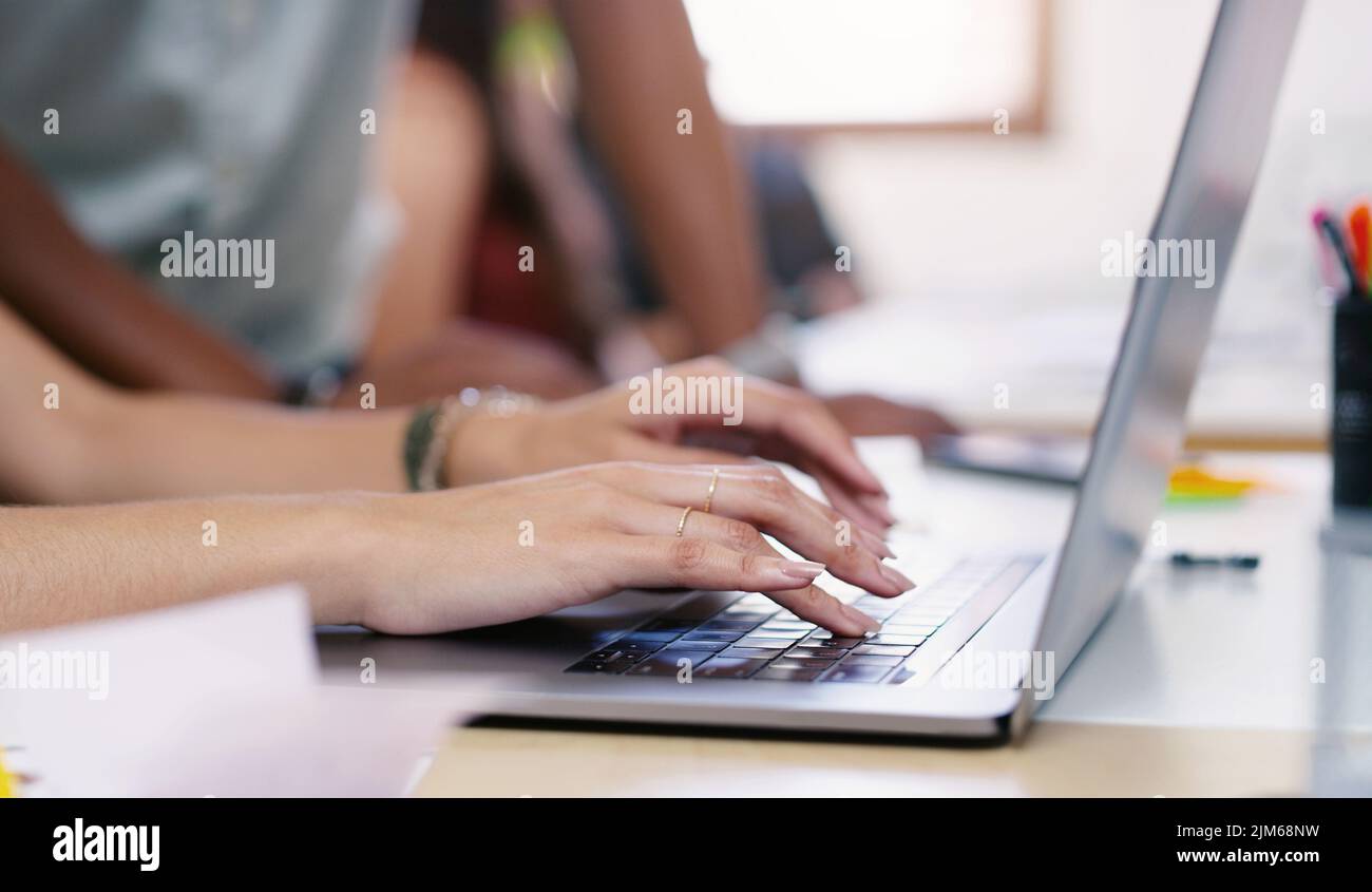 Die besten Designressourcen sind nur einen Klick entfernt. Eine unkenntliche Geschäftsfrau und ein Geschäftsmann, der in einem modernen Büro einen Laptop benutzt. Stockfoto