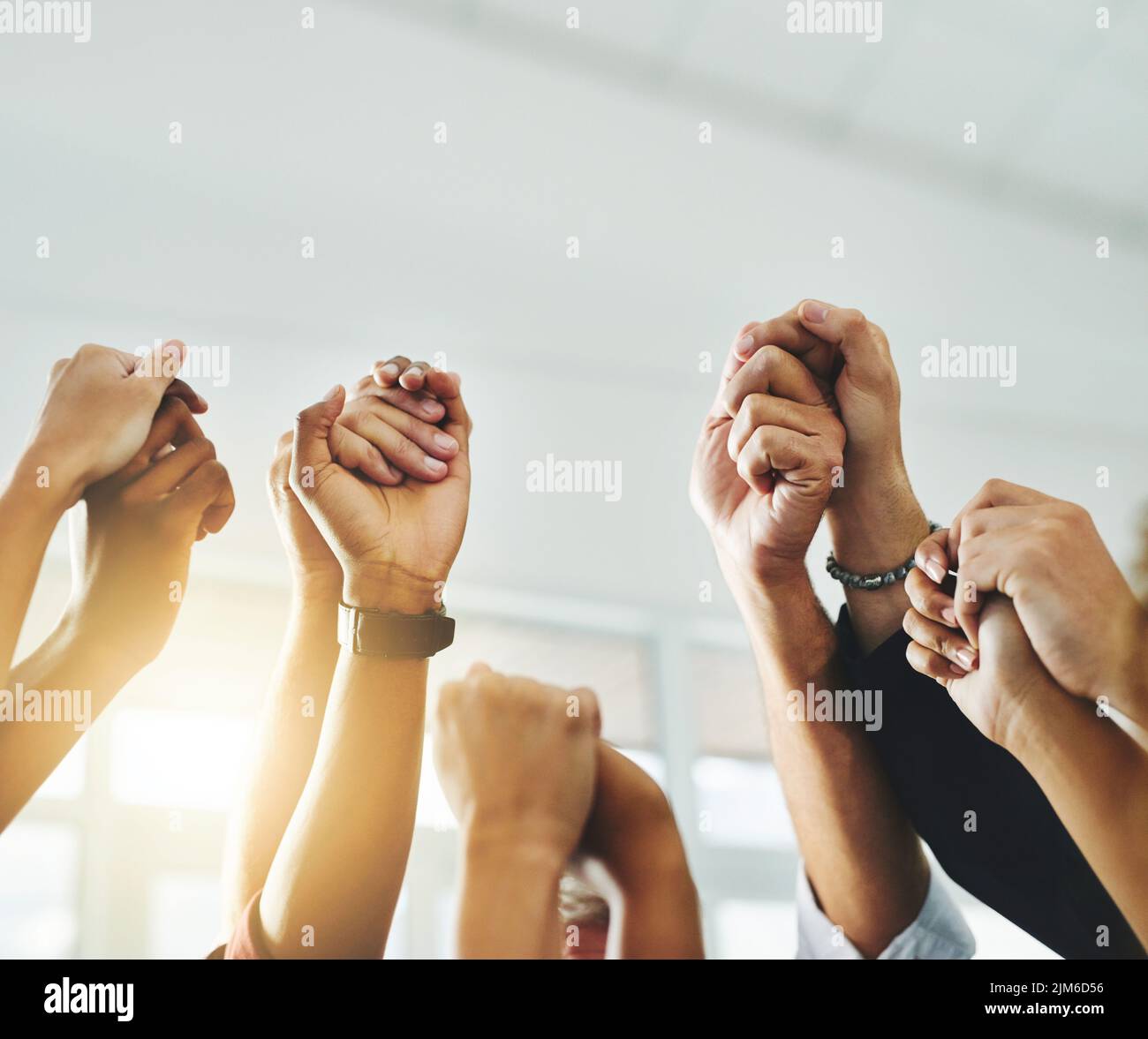Menschen heben ihre Arme und halten sich die Hände, um gemeinsam als Team und Gruppe in Einheit zu protestieren. Männer und Frauen zeigen Teamarbeit Stockfoto