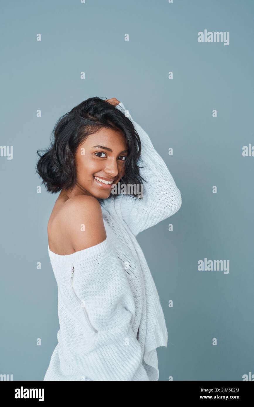 Lächle und überteil es. Eine schöne junge Frau, die vor einem blauäugigen Hintergrund posiert. Stockfoto