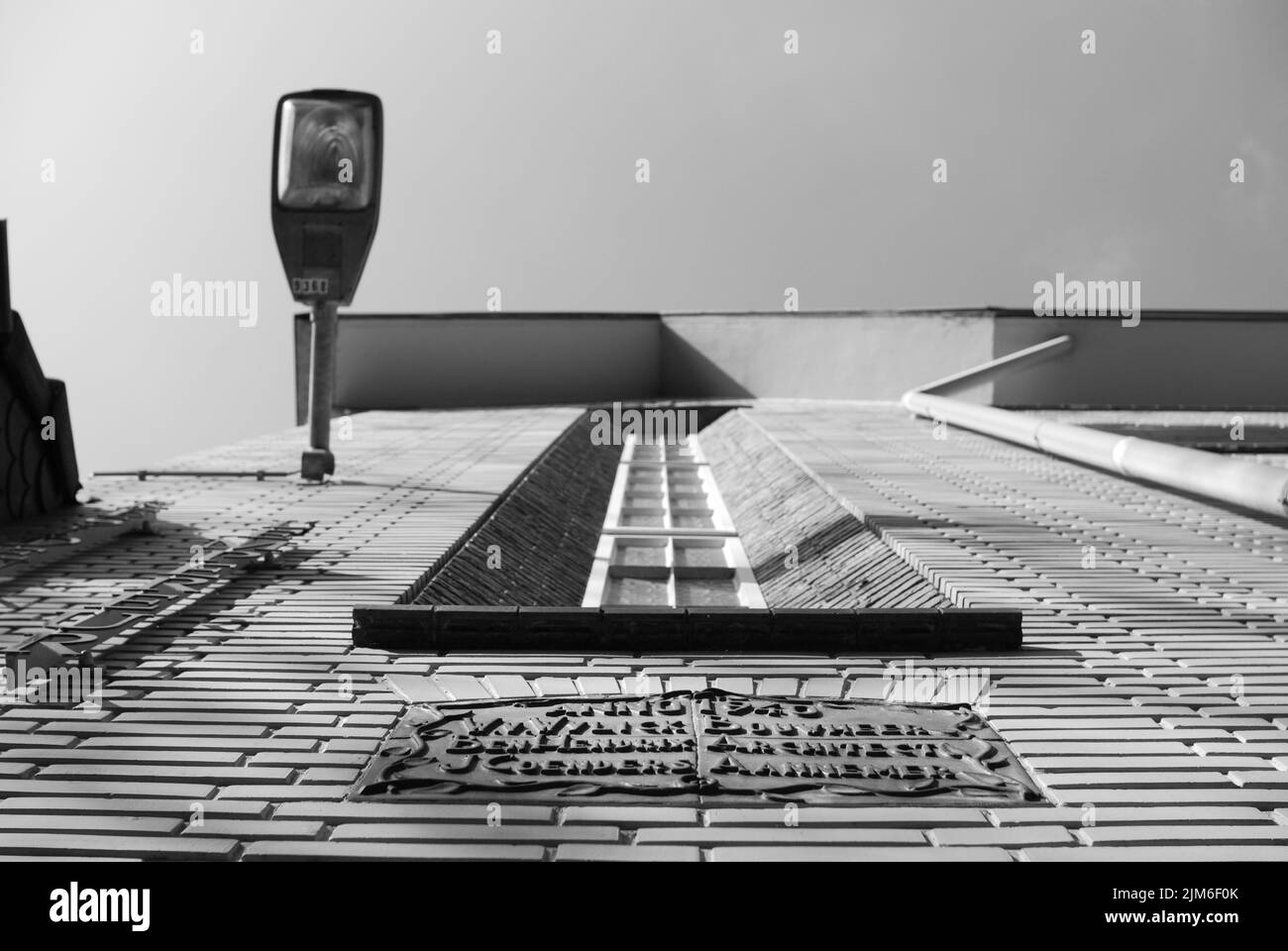 Ein grauer niedriger Winkel, der von einer Ziegelmauer mit einer Laterne auf einem alten Gebäude in Richtung Himmel geschossen wurde Stockfoto Ein grauer niedriger Winkel, der von einer Ziegelmauer mit einer Laterne auf einem alten Gebäude in Richtung Himmel geschossen wurde Stockfoto