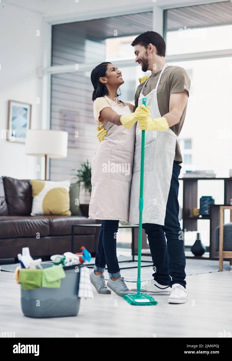 Tun der Haushaltsaufgabe Tango. Ein glückliches junges Paar tanzen beim Wischen des Bodens zu Hause. Stockfoto