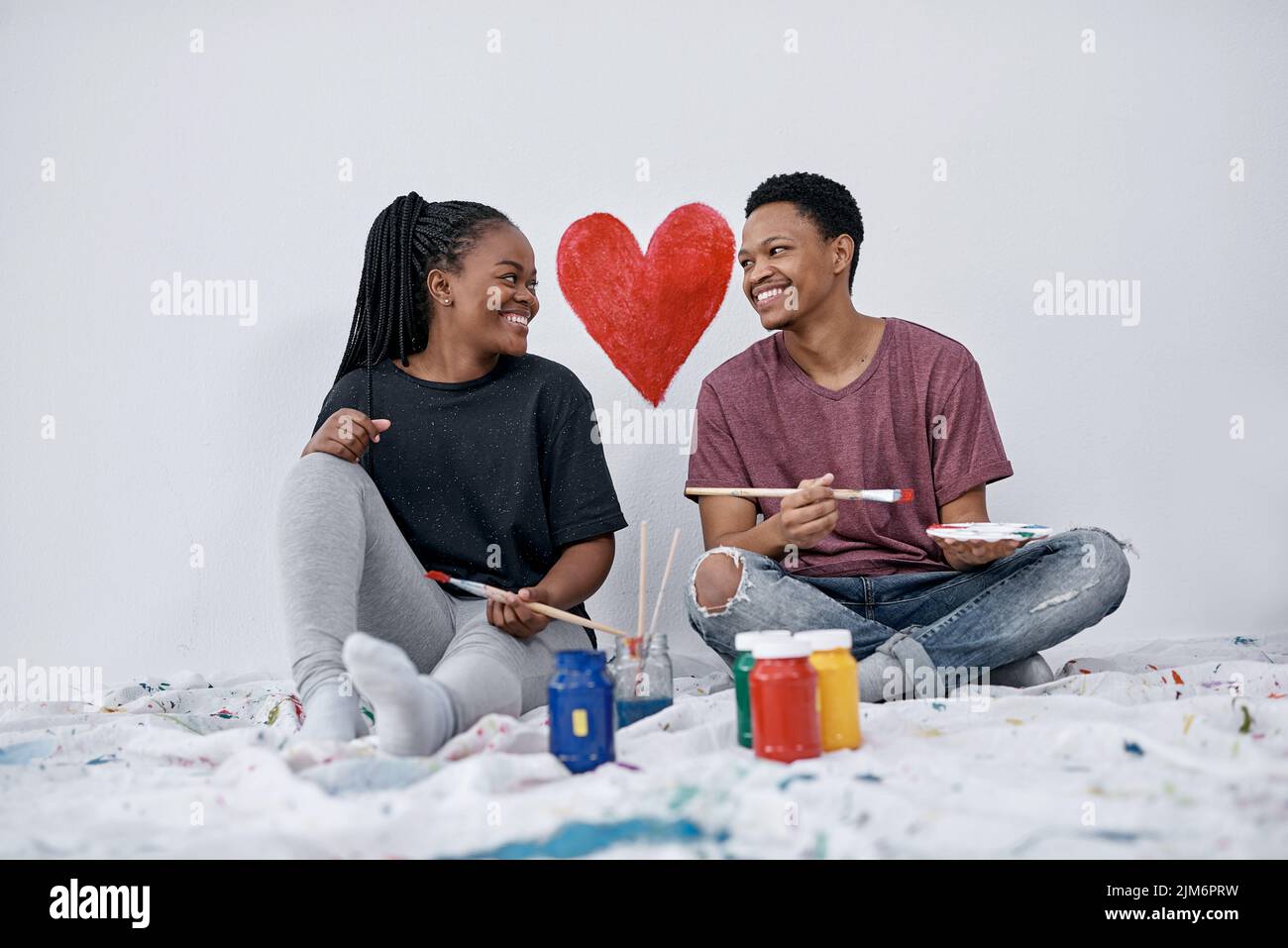 Liebe ist das Herz eines glücklichen Hauses. Ein junges Paar malt ein Herz an eine Wand. Stockfoto