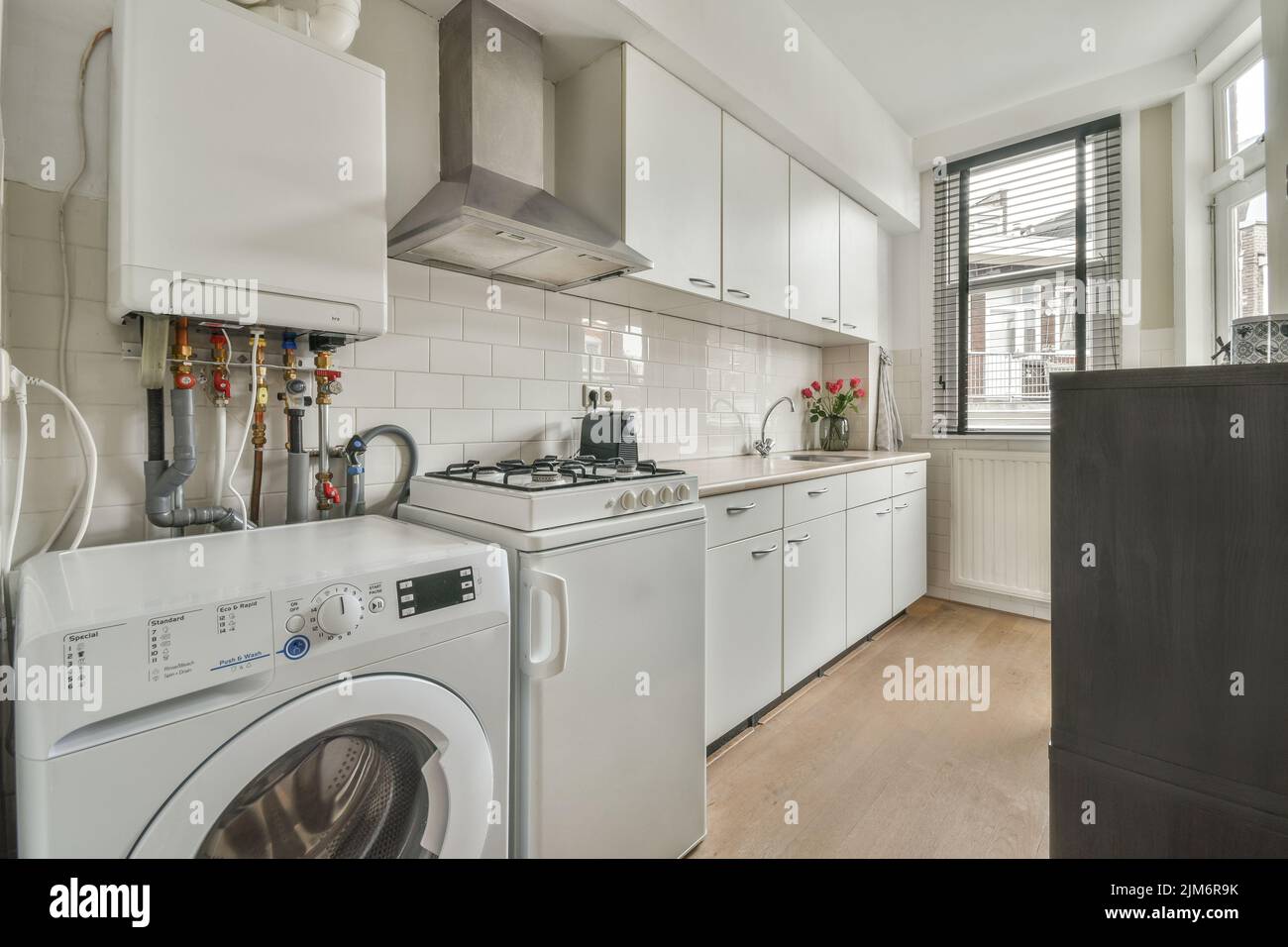 Offene Küche mit Schränken aus dunklem Holz und Pendelleuchten in luxuriösem Apartment Stockfoto