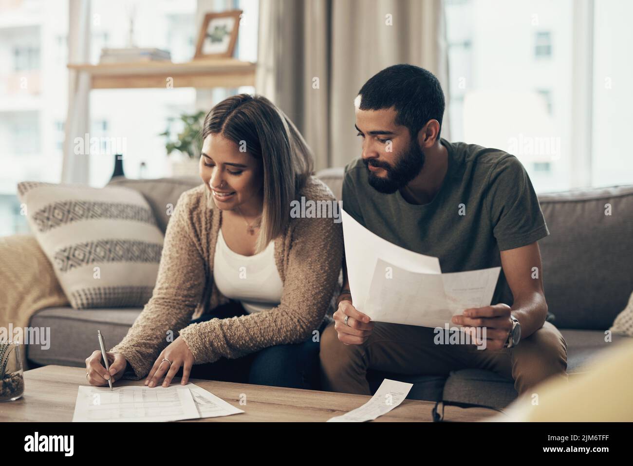 Die richtigen Schritte zu Unternehmen, um auf finanzieller Schiene zu bleiben. Ein junges Paar, das zu Hause über Papierkram geht. Stockfoto