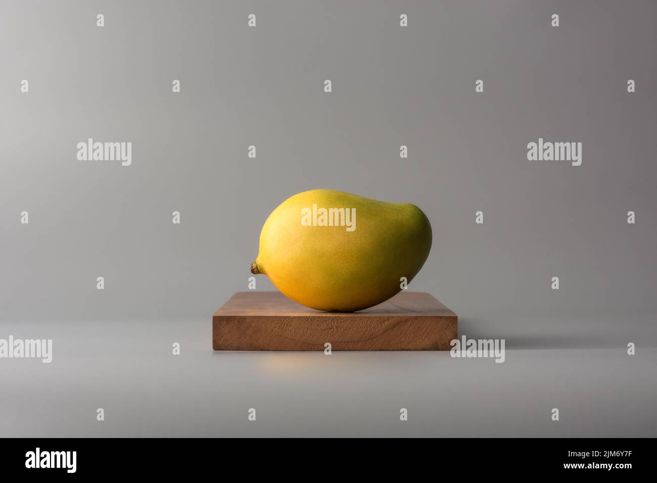 Reife Mango, tropische Früchte auf Holzplatte, neutralgrauer Hintergrund Stockfoto
