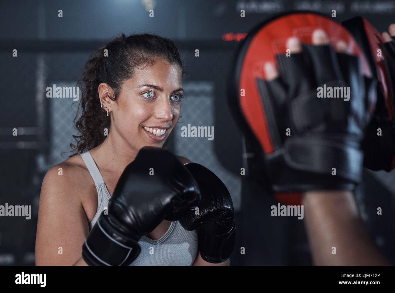 Eine großartige Möglichkeit, Ihre Ausdauer zu verbessern. Eine junge Frau übt mit ihrem Trainer in einer Boxhalle. Stockfoto