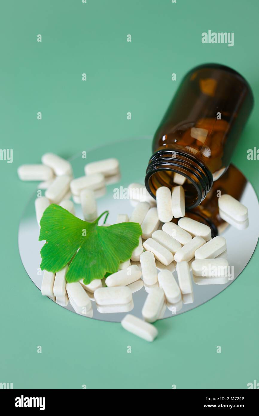 Ginkgo biloba Pillen.Ginkgo biloba Blatt und Tabletten mit Ginkgo biloba Extrakt auf grünem Hintergrund.Vorbereitungen mit Ginkgo biloba Extrakt.Alternative Stockfoto