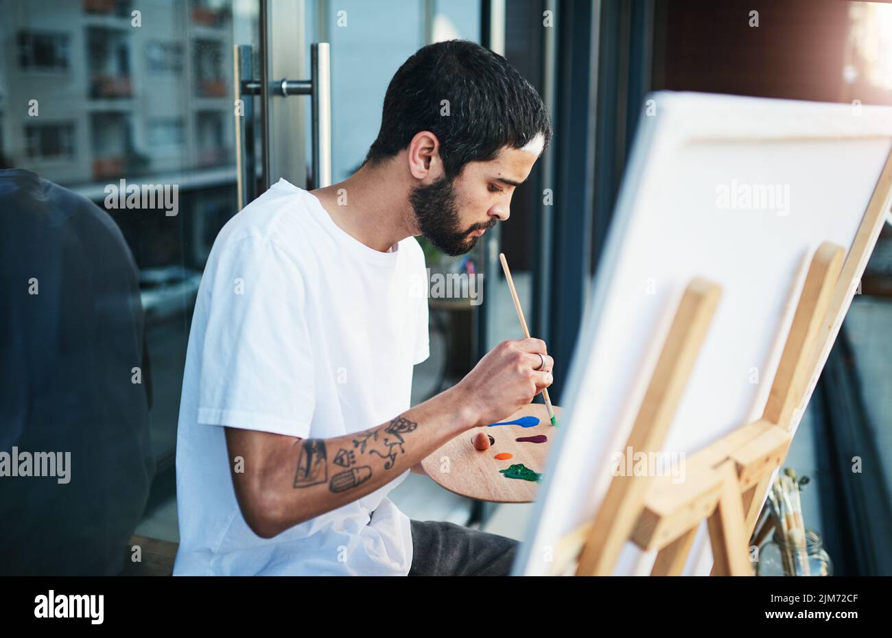 Öffnen Sie Ihren Geist für künstlerische Möglichkeiten. Ein Mann, der ein Gemälde macht, während er zu Hause auf dem Balkon sitzt. Stockfoto