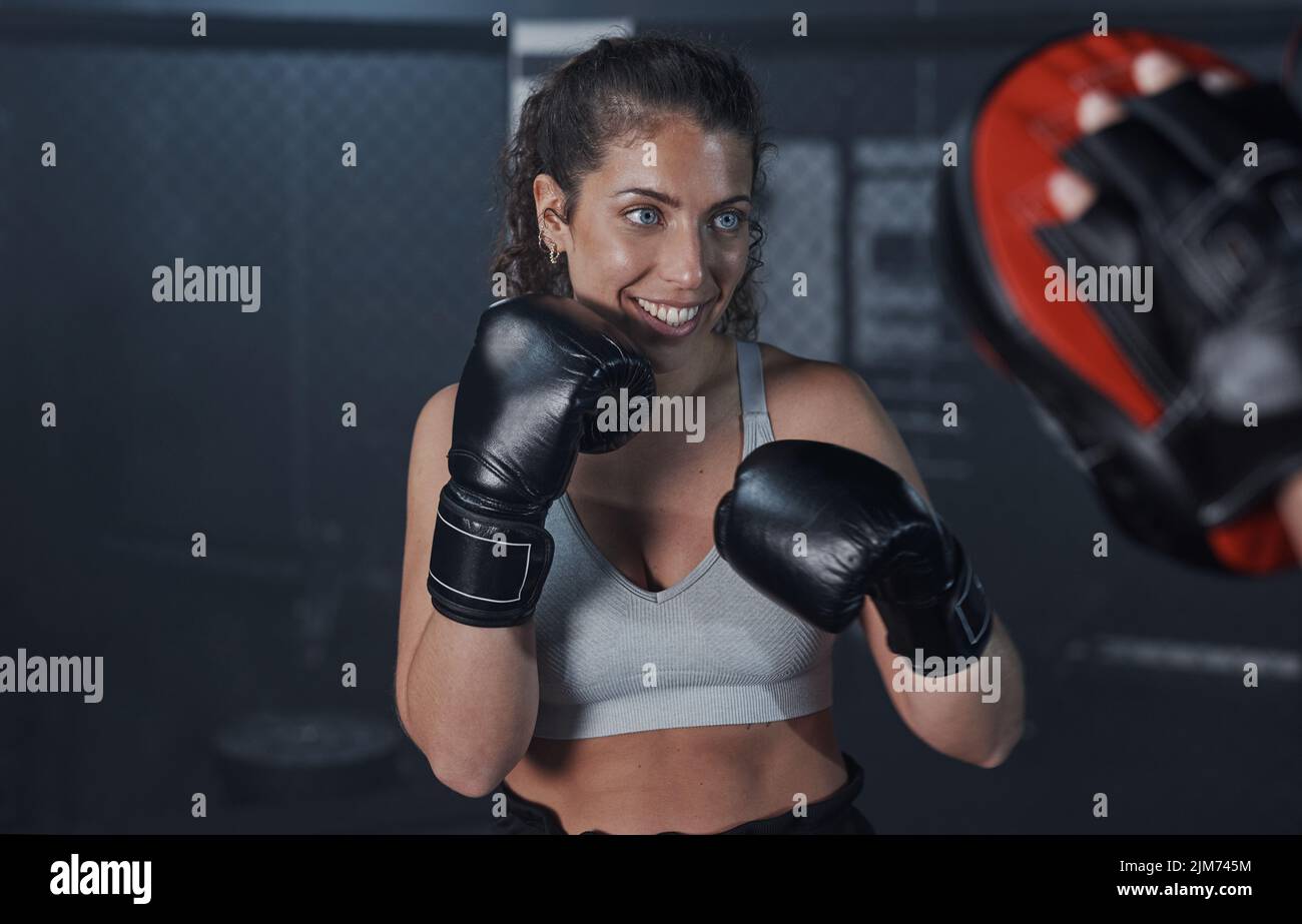 Das kalorienarme Workout, das einen Schlag packt. Eine junge Frau, die mit ihrem Trainer in einer Boxhalle trainiert. Stockfoto