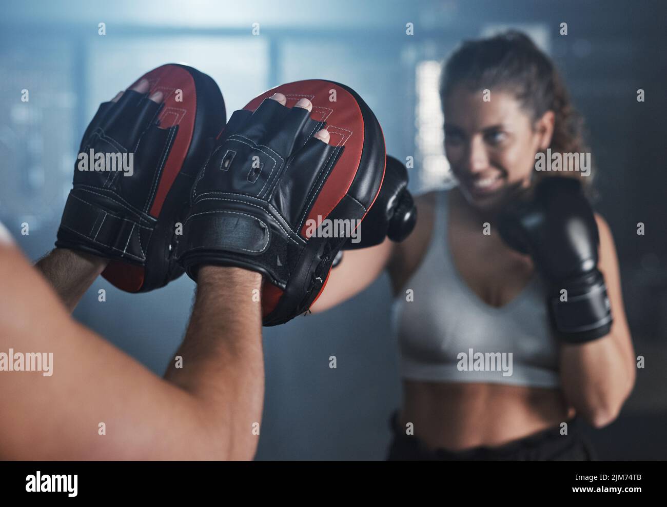 Eine junge Frau, die mit ihrem Trainer in einer Boxhalle trainiert. Stockfoto
