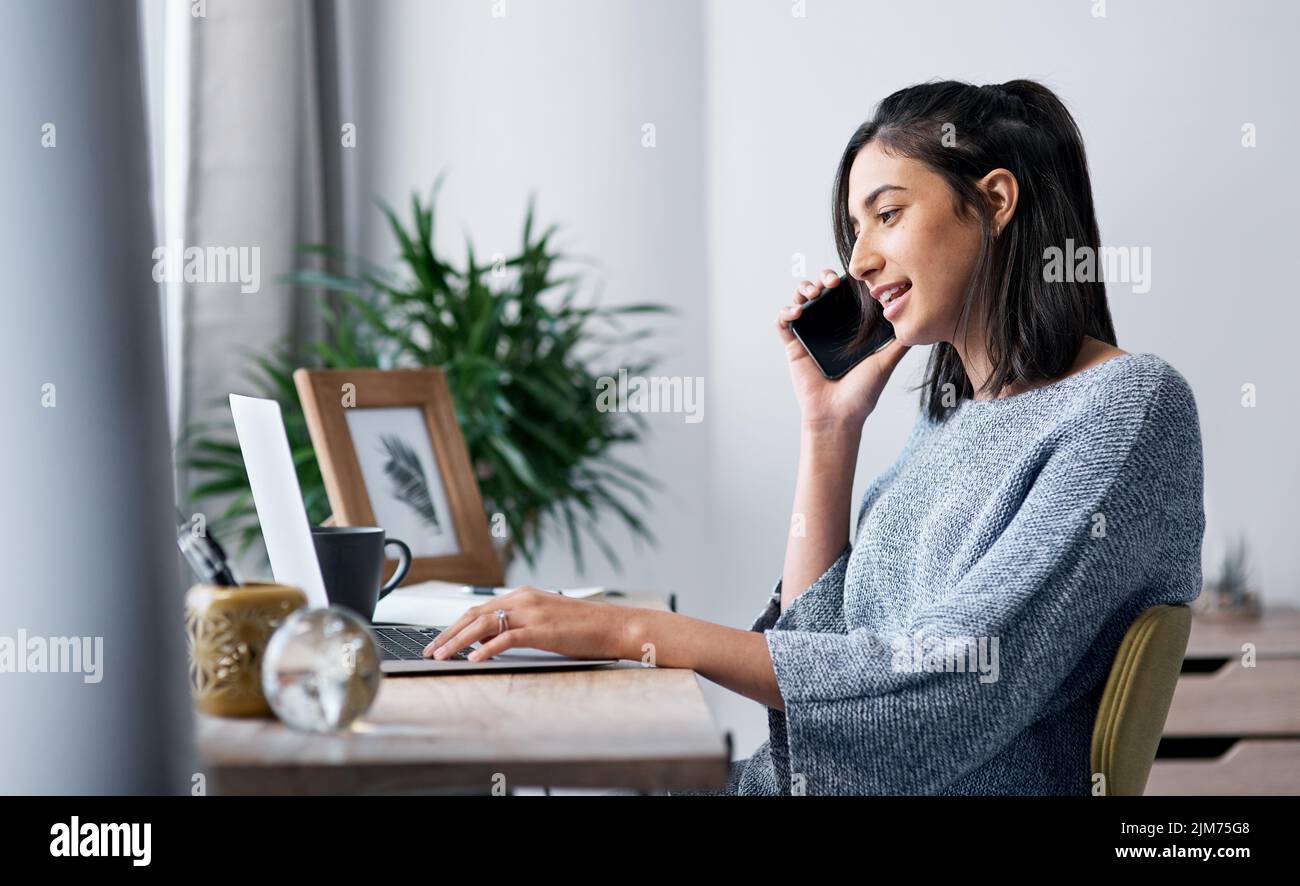 Ein junger Mann, der von zu Hause aus mit einem Laptop und einem Smartphone arbeitet. Stockfoto