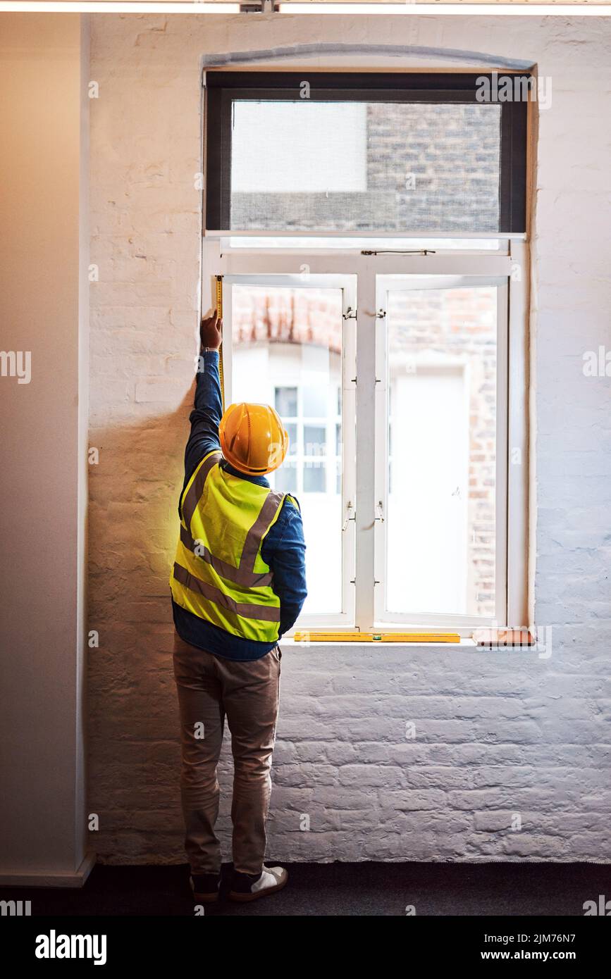 Nun müssen dieses Fenster ersetzen. Ein Ingenieur, der Messungen auf einer Baustelle nimmt. Stockfoto