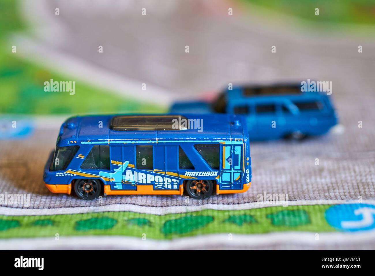 Ein selektiver Fokus eines Mattel Matchbox Spielzeugmodells Flughafenbus auf einer Spielmatte Stockfoto