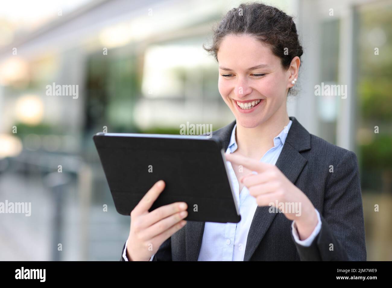 Glückliche Führungskraft mit digitalem Tablet, die auf der Straße unterwegs ist Stockfoto