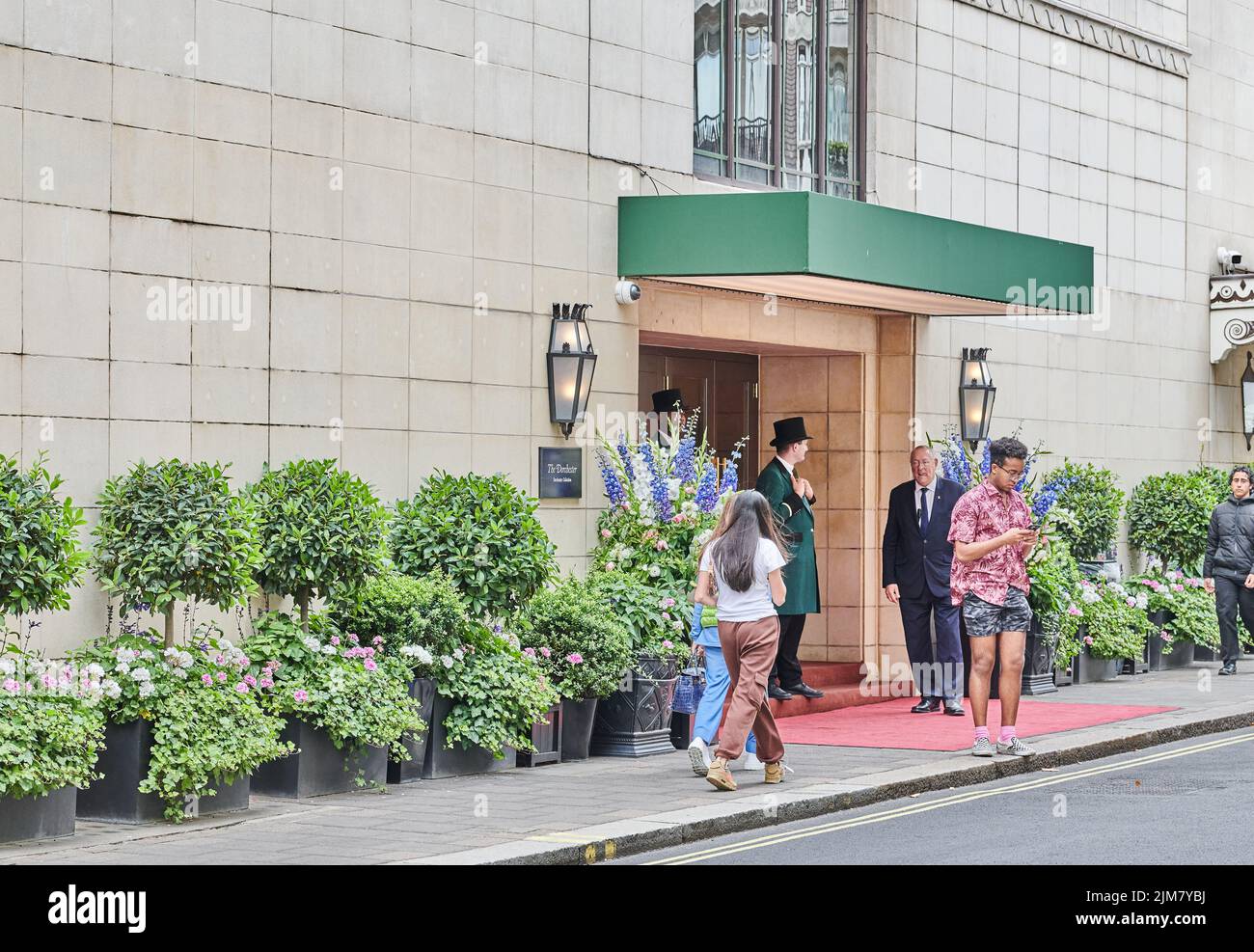 Sicherheitstüren und ein Gast vor dem Haupteingang des Dorchester Hotels Mayfair, London, England. Stockfoto