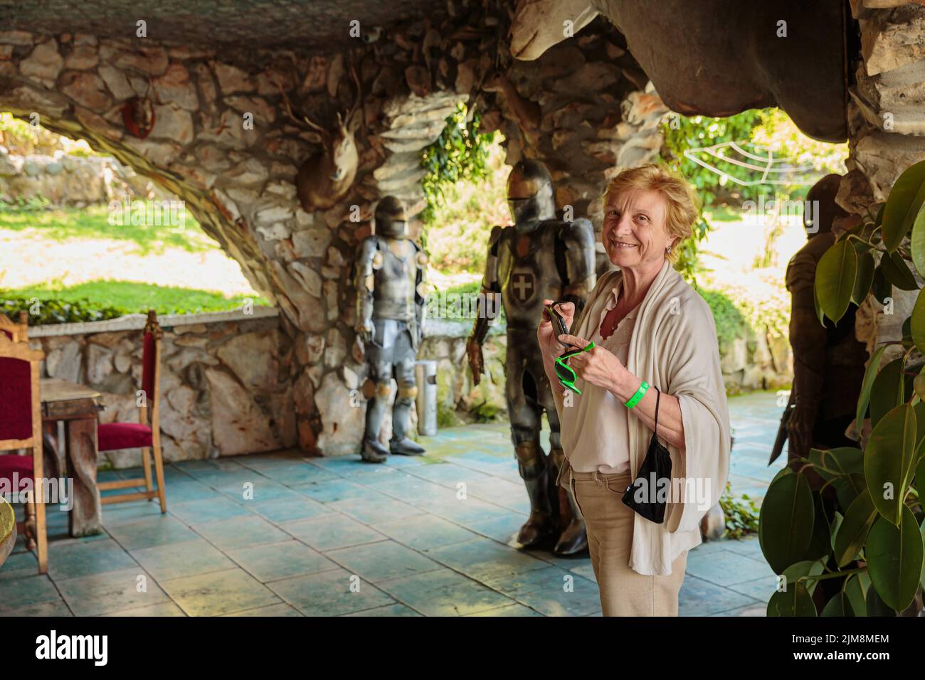 Ältere Touristenfrau, die in einem alten Schloss Fotos auf ihrem Telefon machte Stockfoto