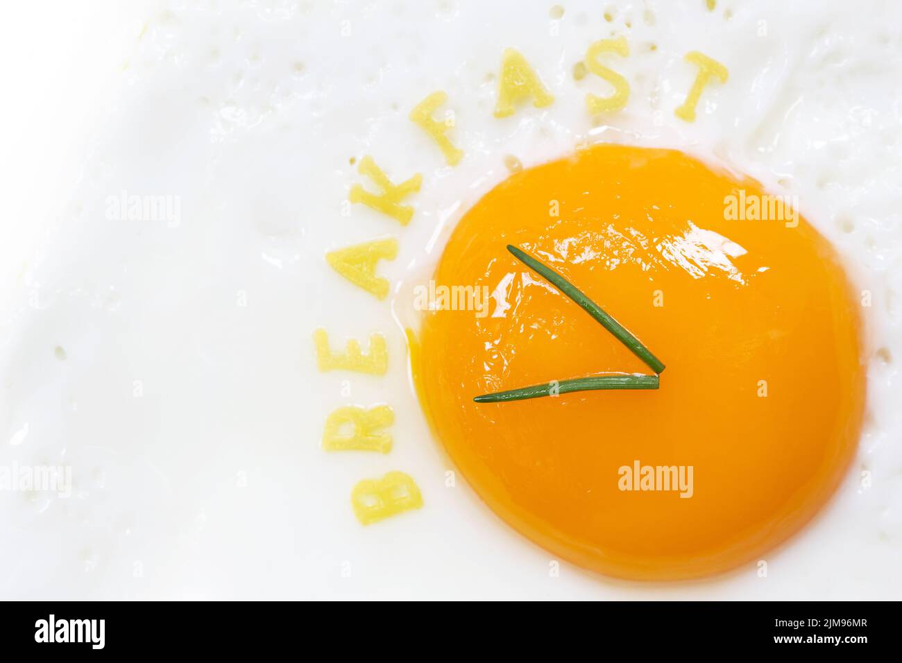 Spiegeleier mit sonniger Seite in Form einer Uhr mit Nudelbuchstaben zum Frühstück Stockfoto