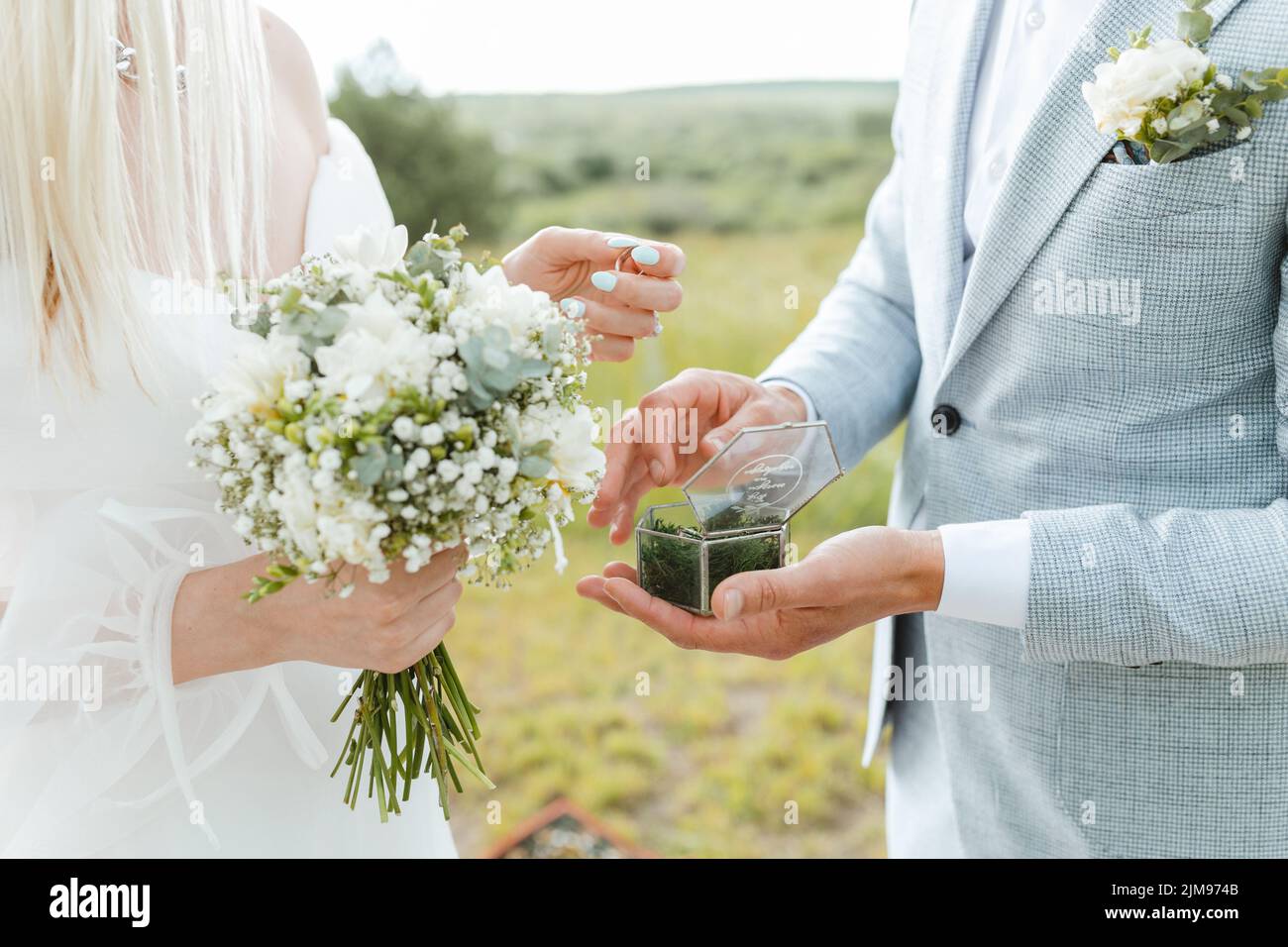 Nahaufnahme der Braut, die ihre Hand dem Bräutigam gibt, um ihren Ring während der Hochzeitszeremonie anzuziehen. Verheiratetes Leben und glückliches Familienkonzept. Stockfoto