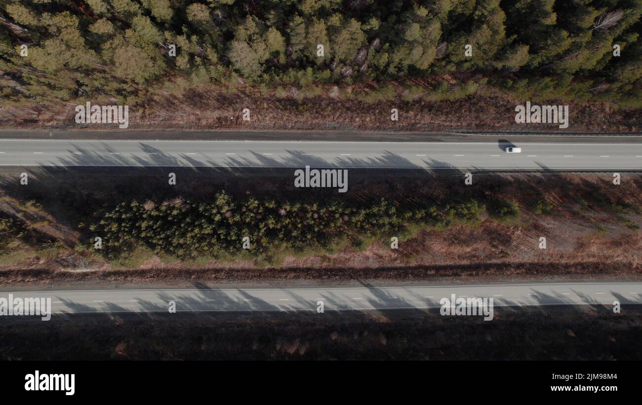 Autobahnstraße zwischen tiefem Wald in Ural, Russland. Schöne herbstliche Naturlandschaft bei tagsüber. Luftaufnahme von einer Drohne Stockfoto