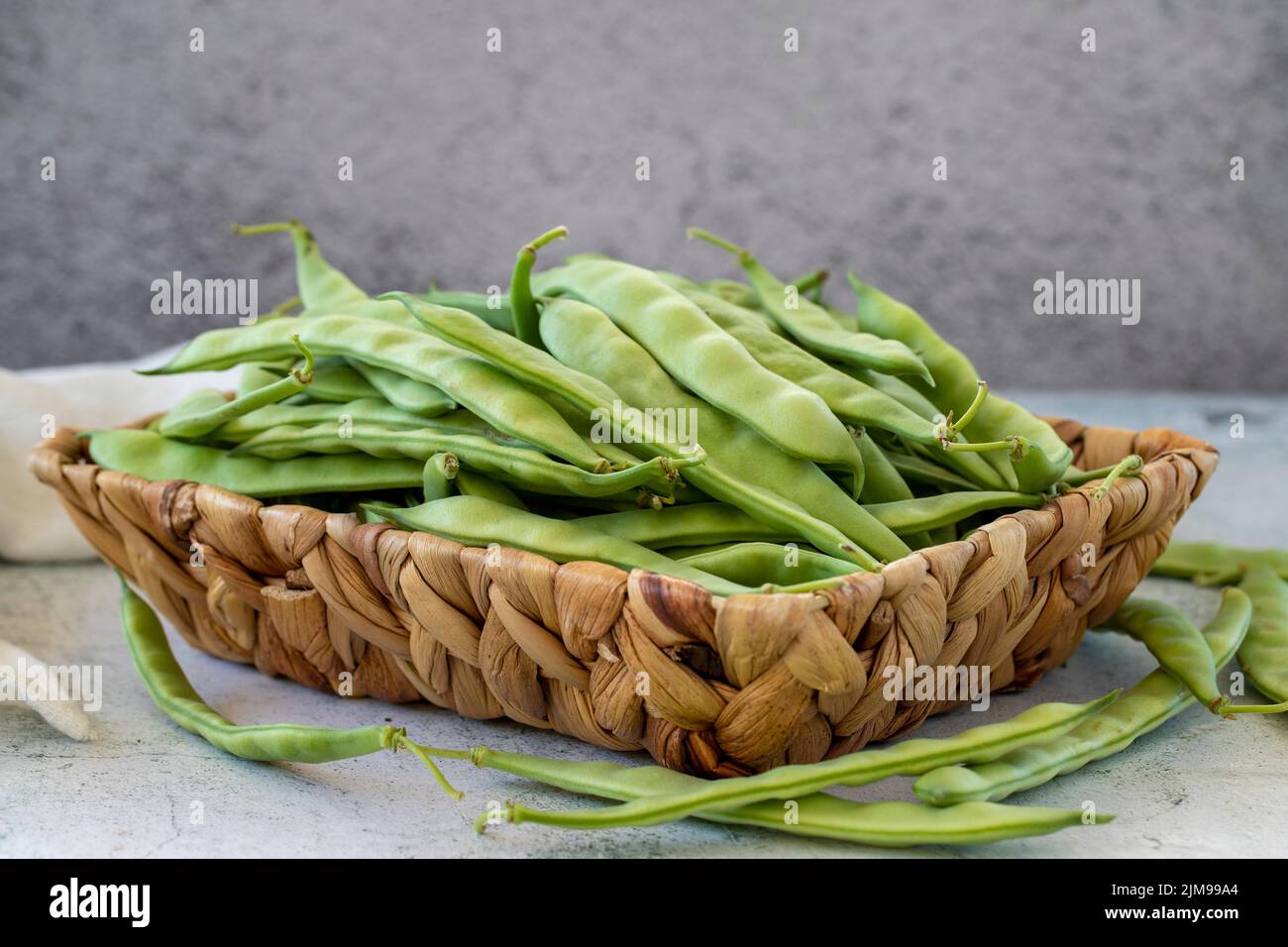 Reife grüne Bohnen. Frische und rohe grüne Bohnen im Korb auf steinernem Hintergrund. Bio-Lebensmittel. Nahaufnahme Stockfoto