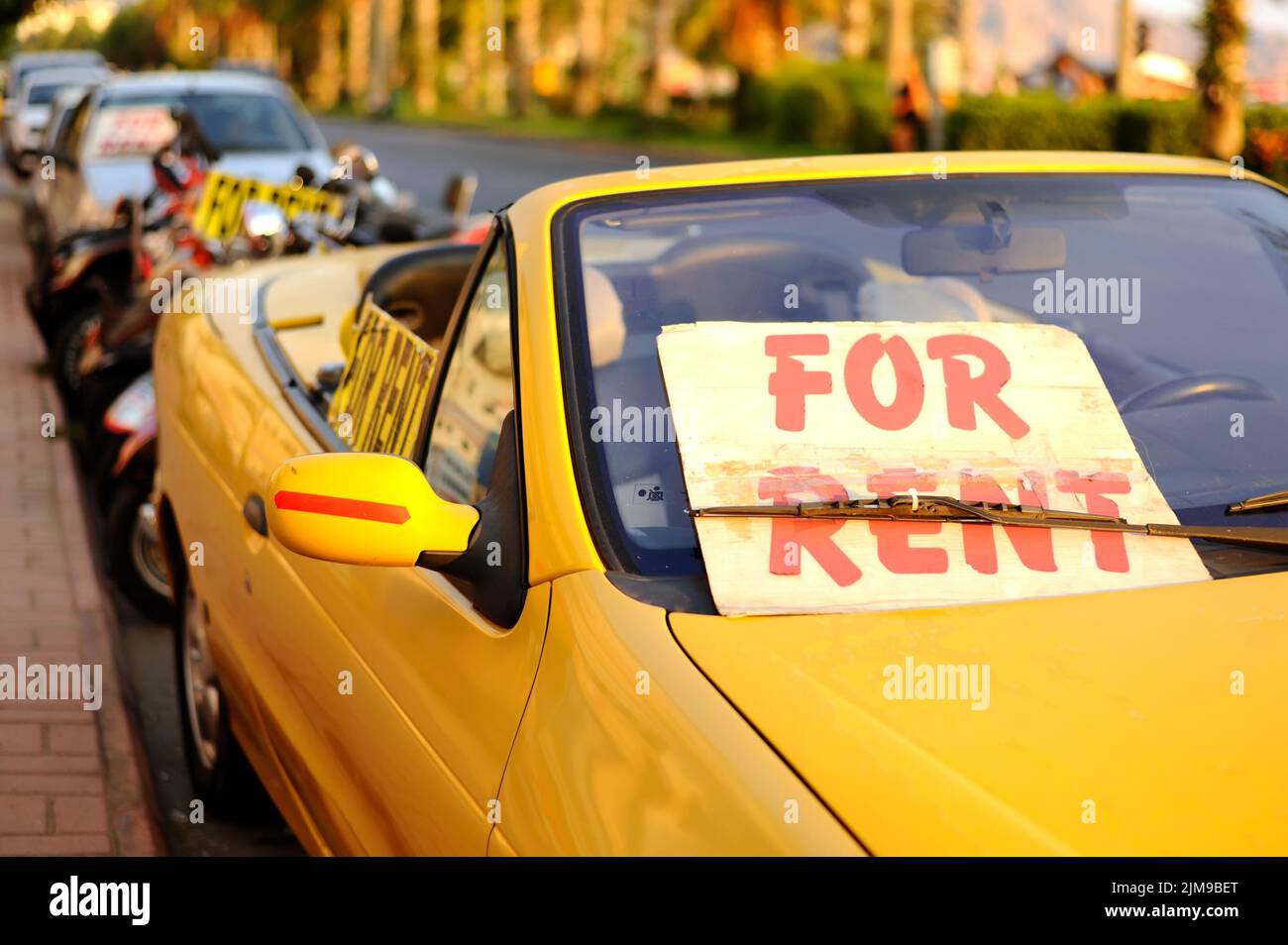 An der Straße befindet sich ein Schild mit der Anmietung eines Autos. Stockfoto