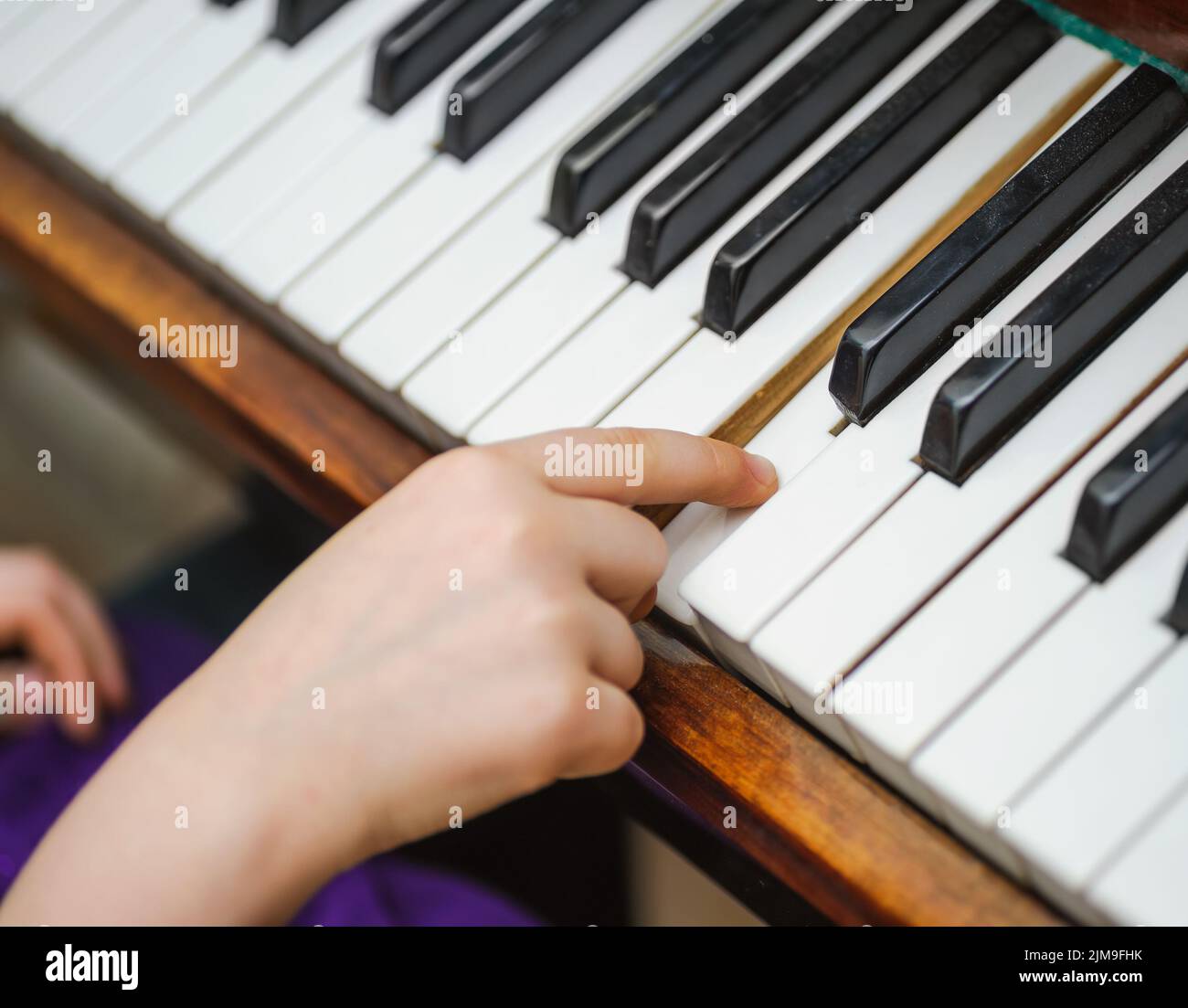 Die Kinder greifen auf einen weißen Klavierschlüssel Stockfoto