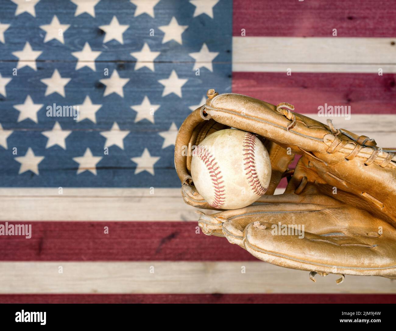 Verwitterter Baseballhandschuh und Ball mit verblassten Brettern, die in den Farben der amerikanischen Flagge lackiert sind Stockfoto