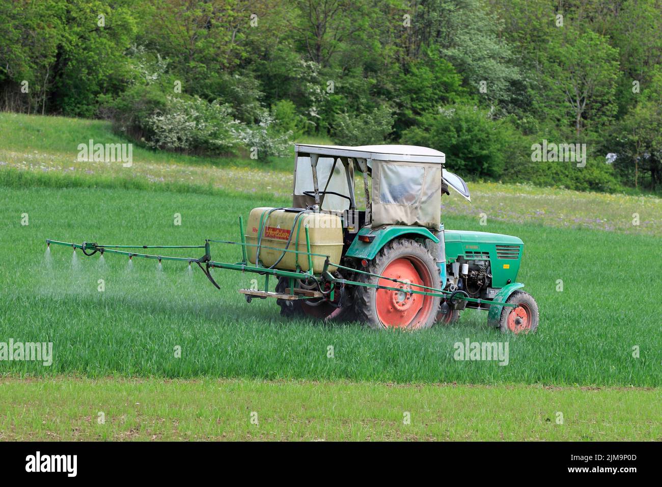 Alter Traktor mit Feldspritze. Stockfoto