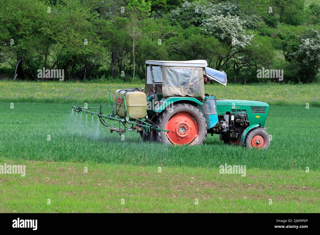 Alter Traktor mit Feldspritze. Stockfoto