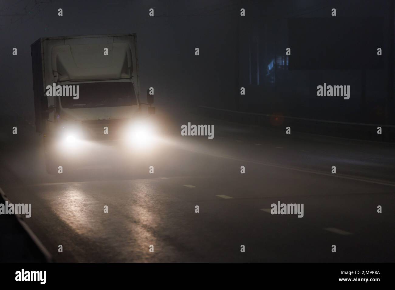 Kleiner, rudelloser, trockener Lieferwagen, der sich auf einer nebligen Straße in der Nacht bewegt Stockfoto