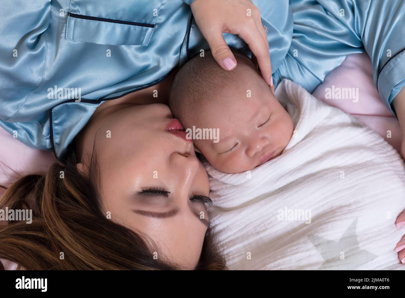 Mutter und Kleinkind schlafen eng zusammen, während sie im Bett schlafen Stockfoto