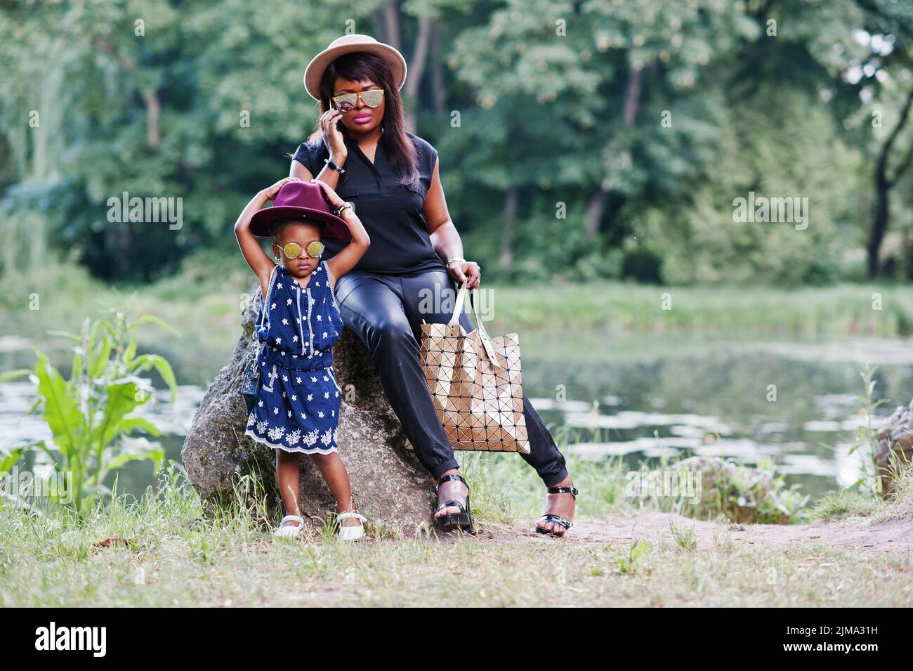 Stilvolle afroamerikanische Mutter und Tochter bei Sonnenbrillen. Schwarze Frau mit Handy Stockfoto