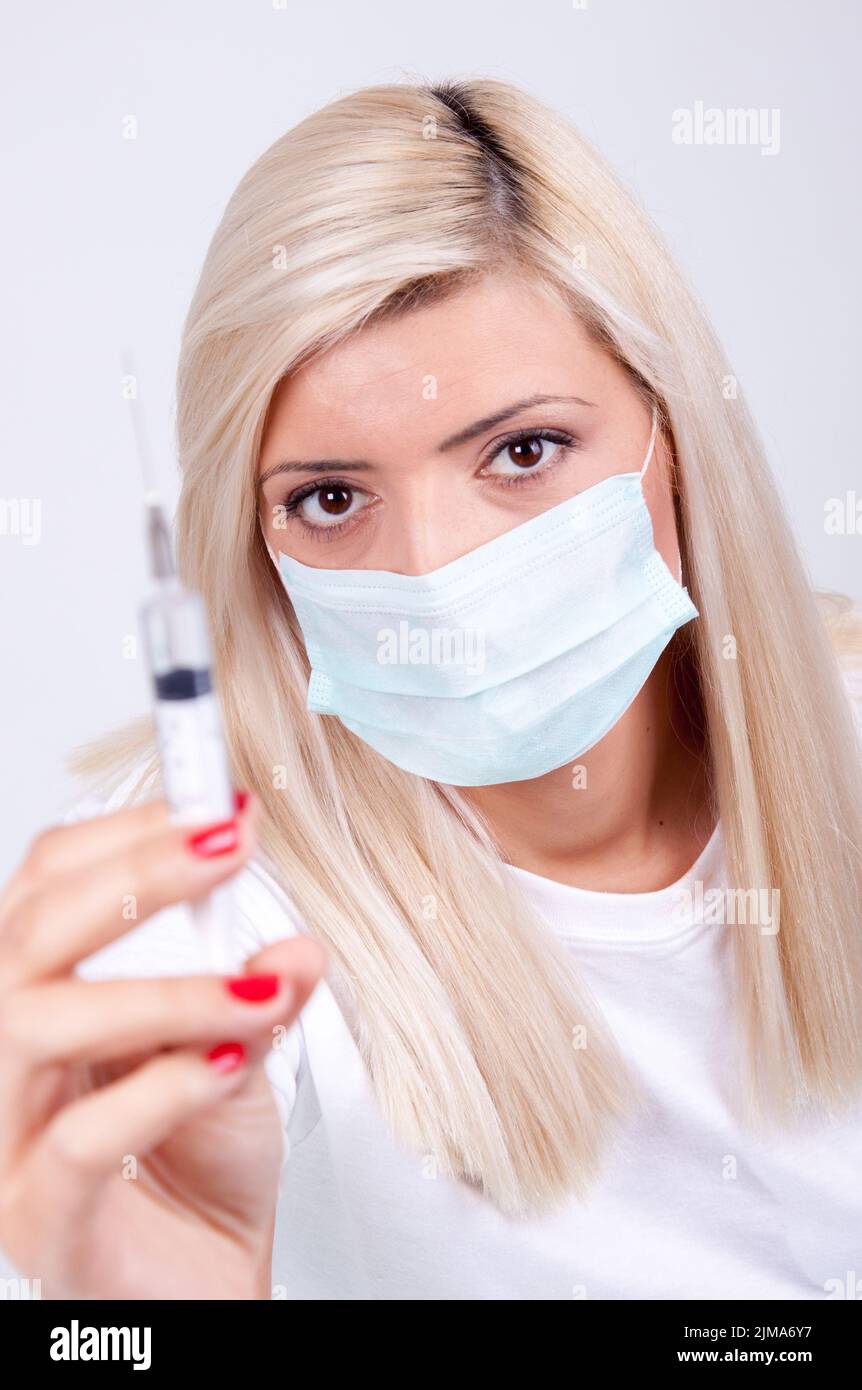 Ärztin oder Krankenschwester in medizinischer Maske mit Spritze mit Injektion, Corona-Virus-Impfstoff Stockfoto