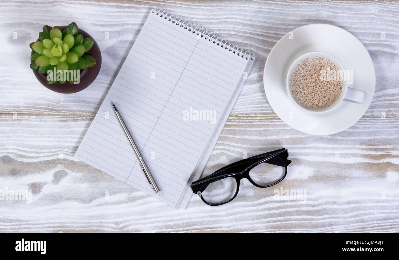 Einfache Schreibwaren mit leerem Notizbuch und Kaffee auf rustikalem Holzschreibtisch Stockfoto
