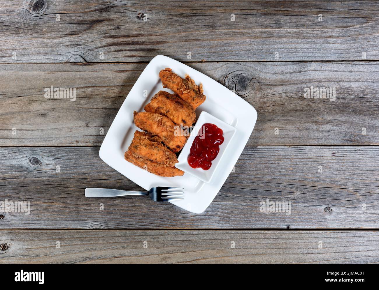 Blick von oben auf frittierten Fisch auf dem Teller auf einem rustikalen Holztisch Stockfoto