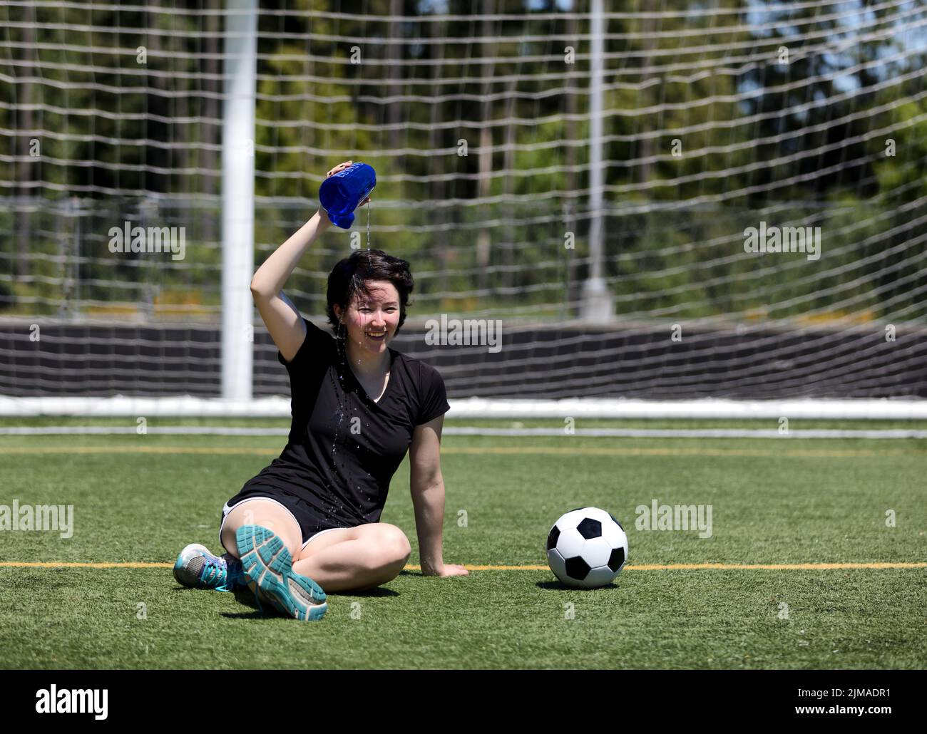 Teen girl goss Wasser auf ihren Kopf während eines heißen Tages auf dem Fußballfeld Stockfoto