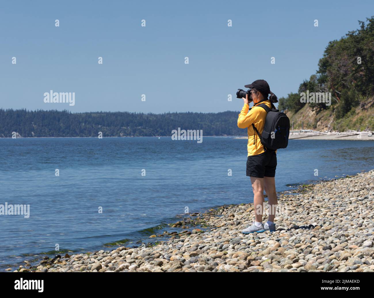 Fotografin, die während eines schönen Sommertages Fotos von einem See gemacht hat Stockfoto