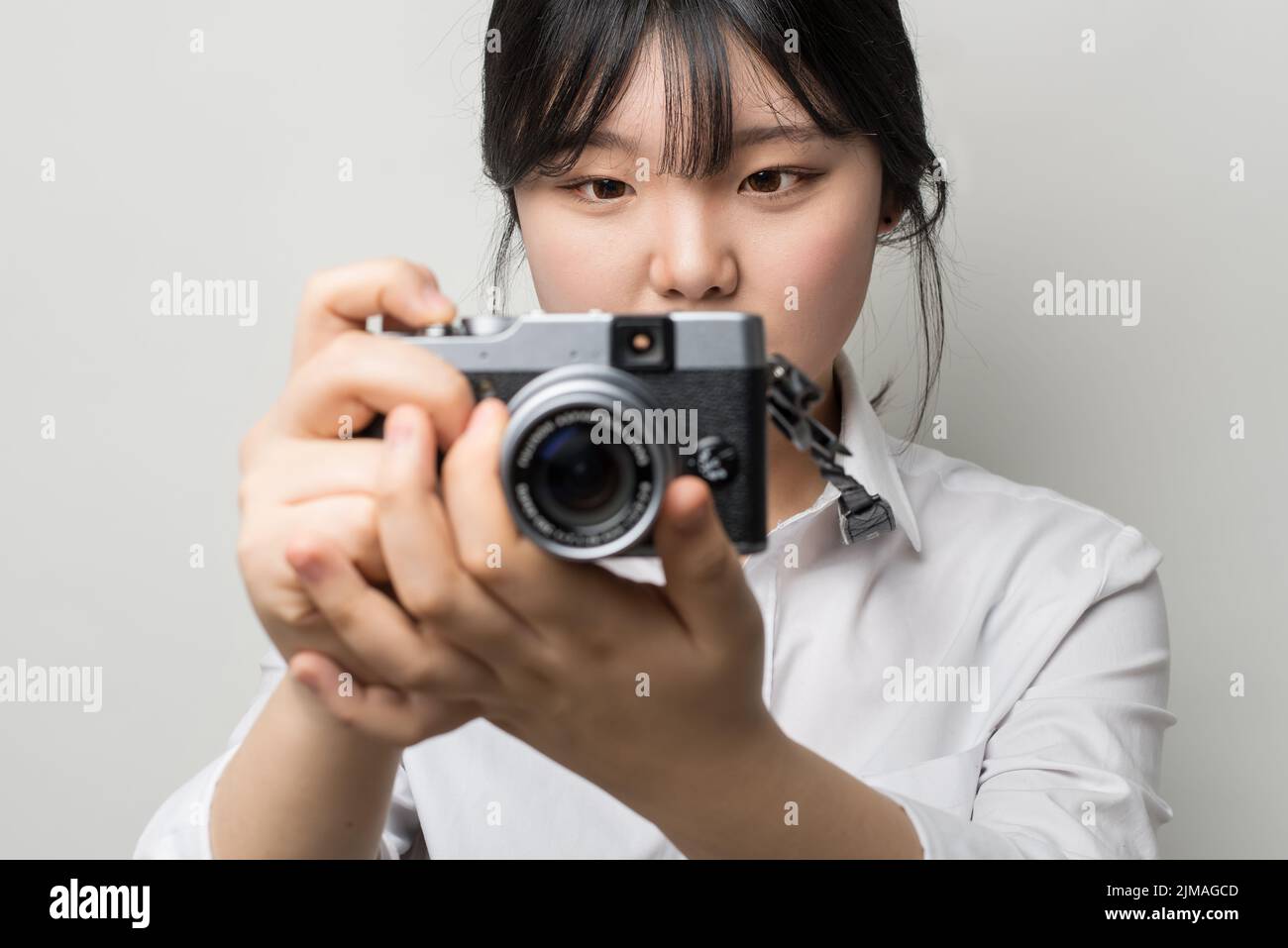 Weibliche Hand hält modernen Kamera (spiegellose Kamera). Kamera in der Hand. Die Augen der Menschen im Mittelpunkt Stockfoto