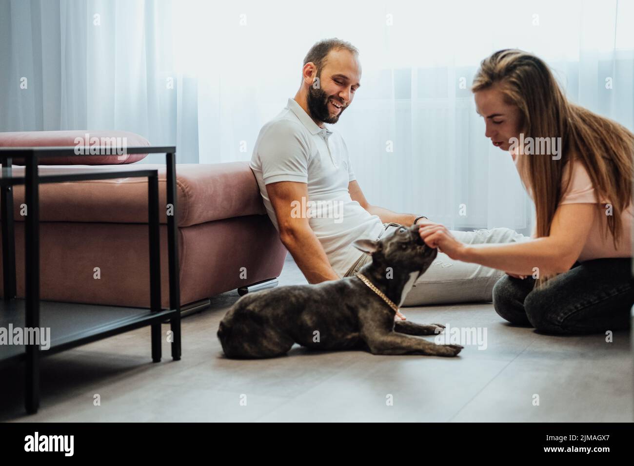 Fröhliche Frau und Mann haben Spaß mit Pet Französisch Bulldog zu Hause Stockfoto