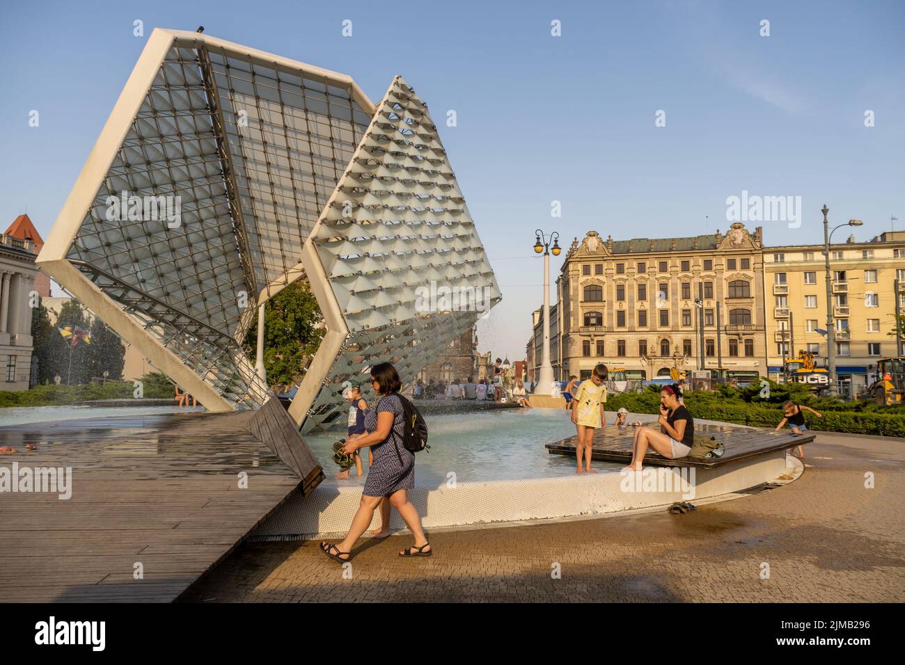 Glückliche Kinder kühlen sich mit Wasser aus dem Brunnen auf dem Plac Wolnosci Platz ab Stockfoto