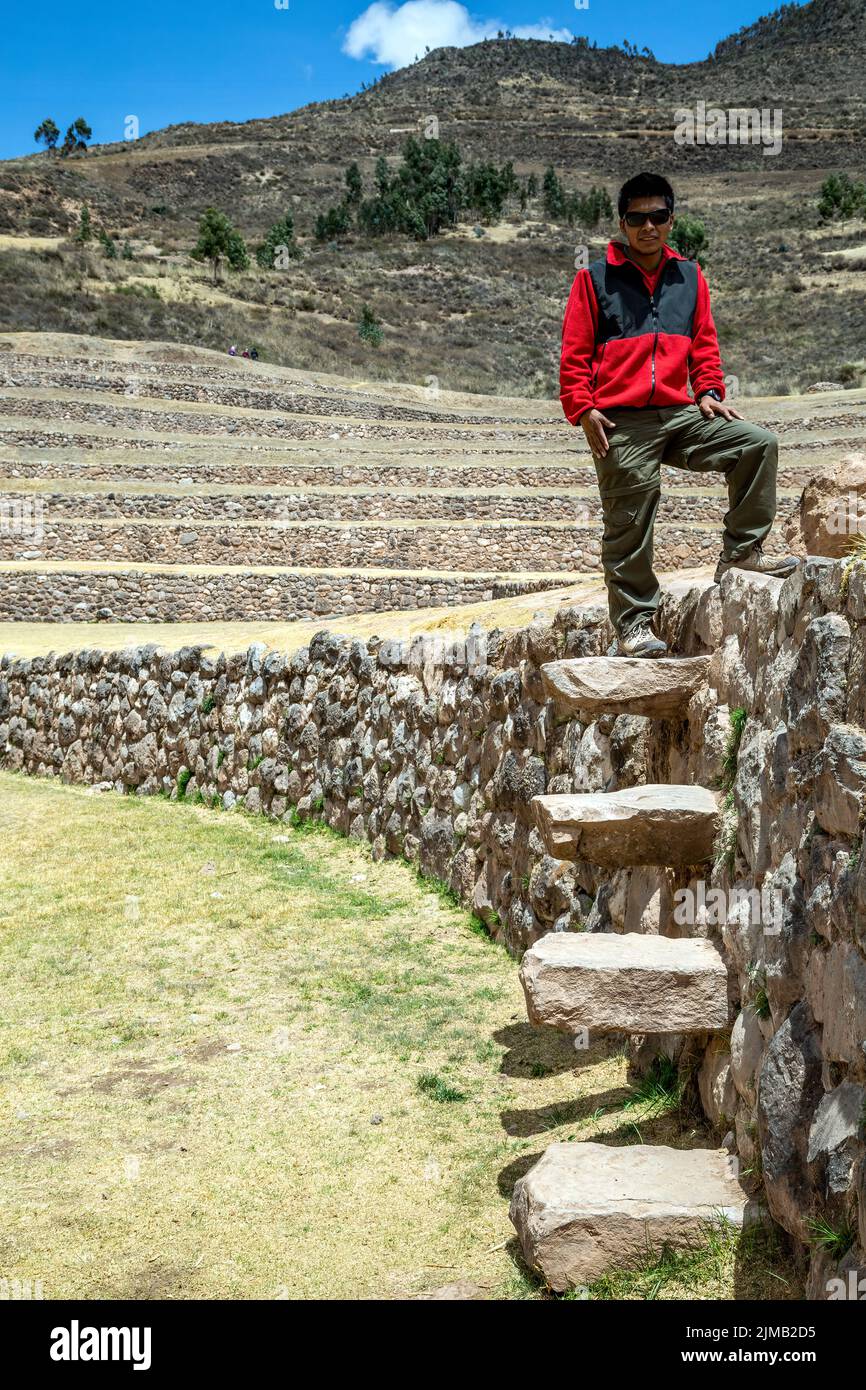 Ed, Reiseführer, auf Steintreppen an der Seite der konzentrischen landwirtschaftlichen Terrasse, Moray Inka Ruinen, Cusco, Peru Stockfoto
