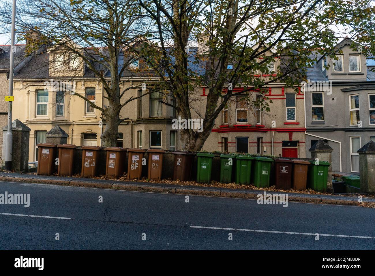 Reihe von grünen und braunen Mülltonnen auf einer Alexandra Road mit Erkerfensterhäusern im Hintergrund. Stockfoto