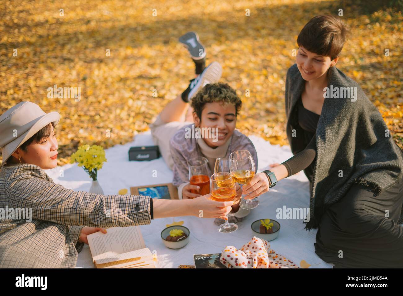 Eine schöne Aufnahme von Freunden, die im Herbst im Park trinken und plaudern Stockfoto